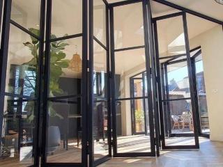 Glazed steel folding door system with multiple slimline panels dividing two rooms
