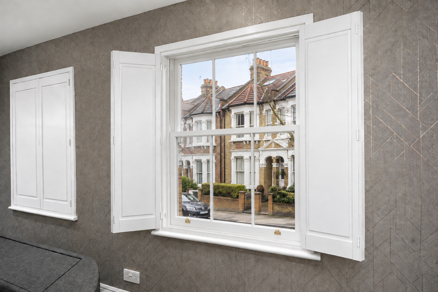 Solid panel shutters folded back against the reveal of a Victorian sash window overlooking a London terrace
