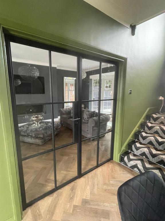 Black glazed steel doors fitted between a hallway and living room with a herringbone timber floor