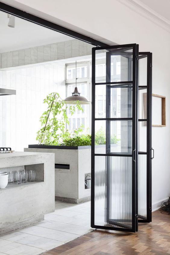 Slim black steel folding doors between a kitchen dining area and an adjoining room